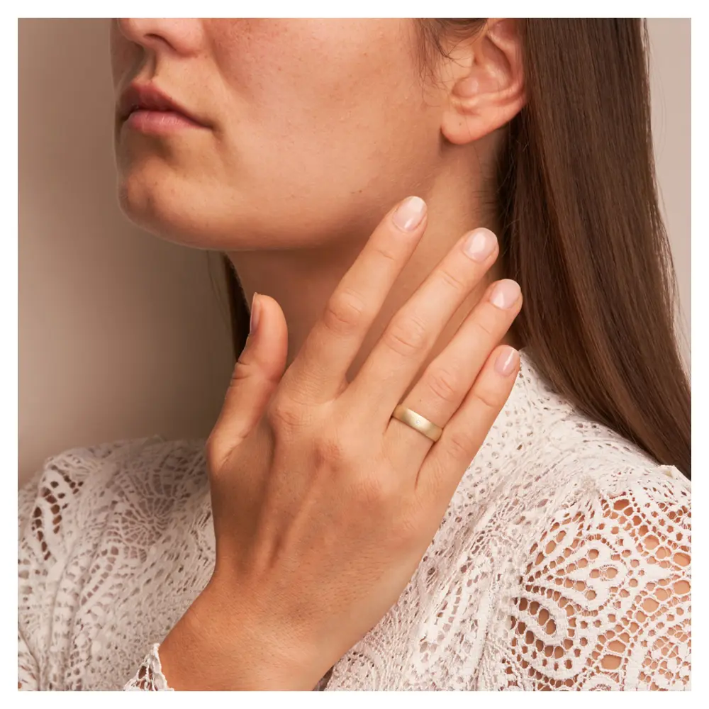 Gelbgold Trauring aus Gelbgold sandmatt mit Diamanten und 5 mm Breite auf Hand am Gesicht