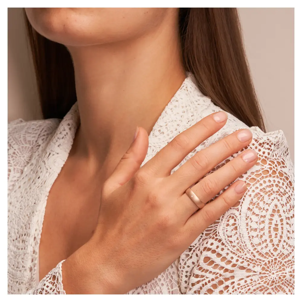 Roségold Eheringe sandmatt mit Diamanten und 5 mm Breite auf Hand am Gesicht