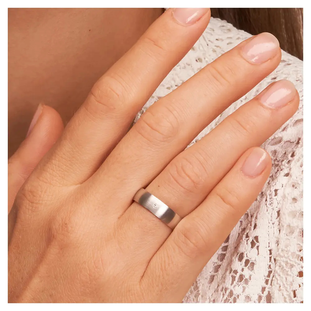 Weissgold Eheringe mit Diamanten und Längsmattierung auf Hand am Gesicht im Zoom