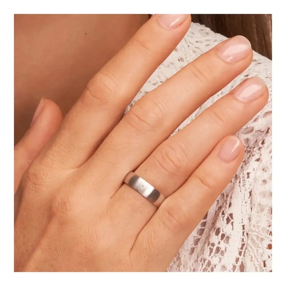 Weissgold Eheringe mit Diamanten und Längsmattierung auf Hand am Gesicht im Zoom