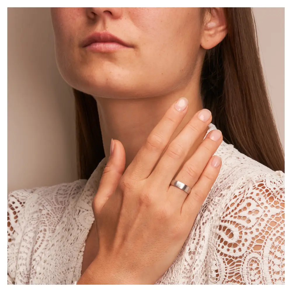 Weissgold Eheringe mit Diamanten und Längsmattierung auf Hand am Gesicht