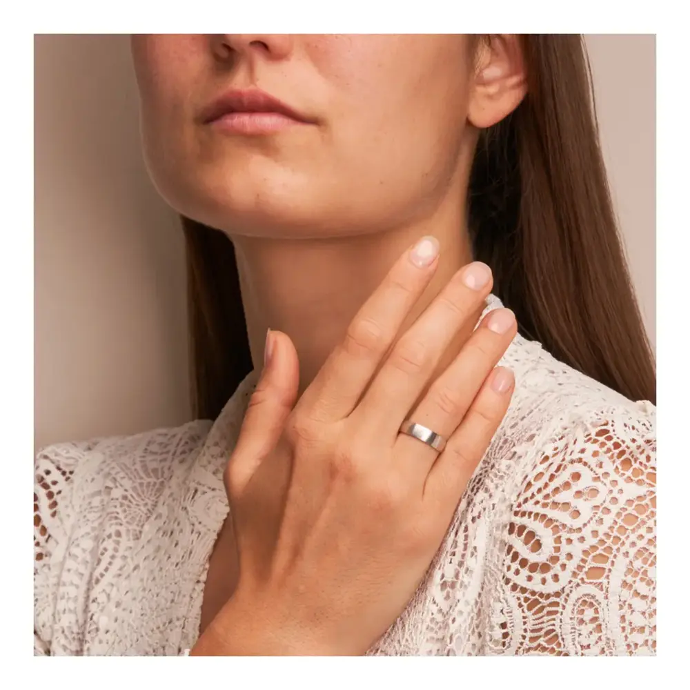 Weissgold Eheringe mit Diamanten und Längsmattierung auf Hand am Gesicht