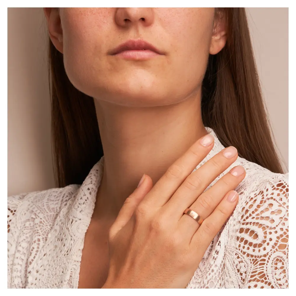 Roségold Ehering mit Diamanten in Längsmattierung auf Hand am Gesicht