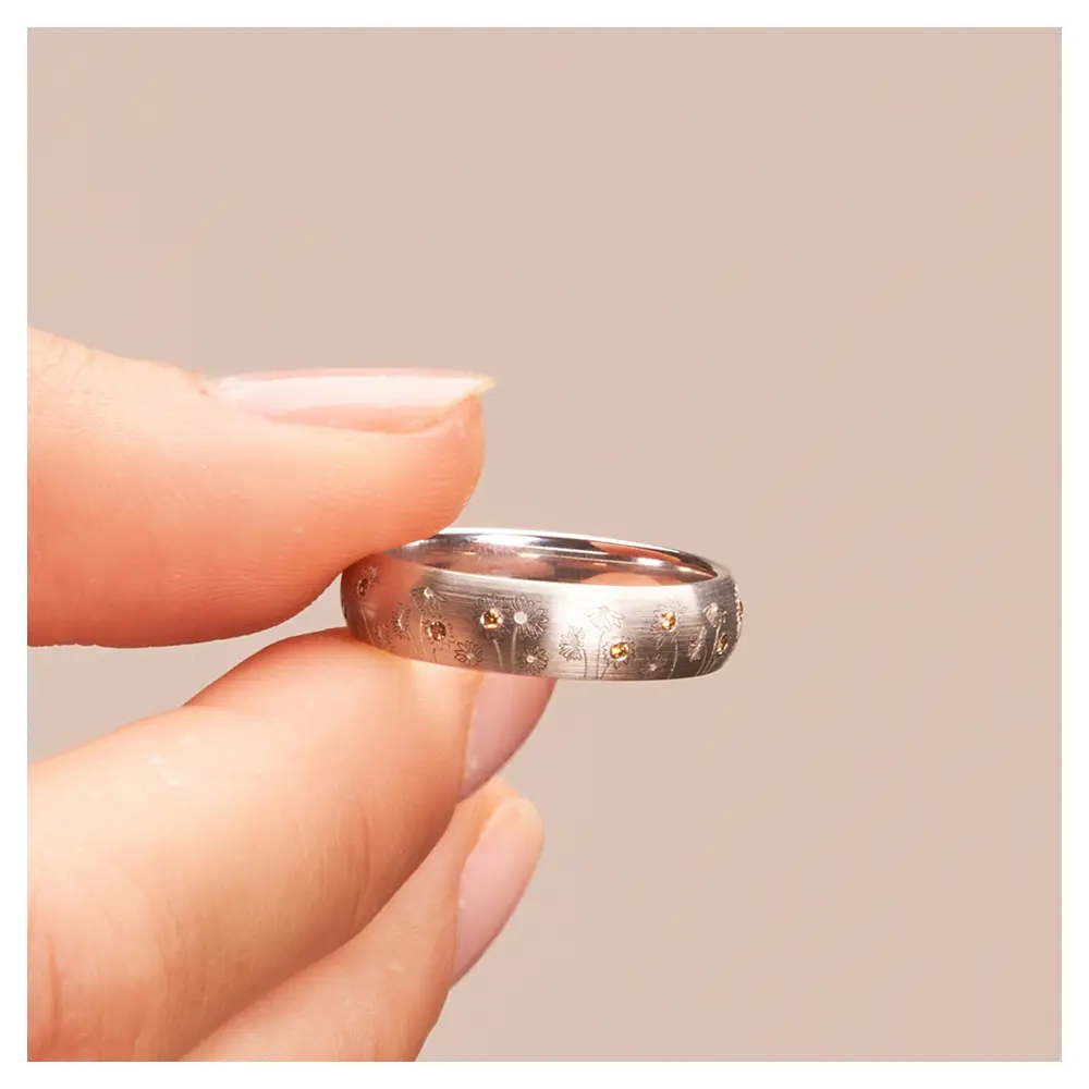 Weißgold Trauring mit Blumen als Dekor und vierzehn Diamanten in Hand