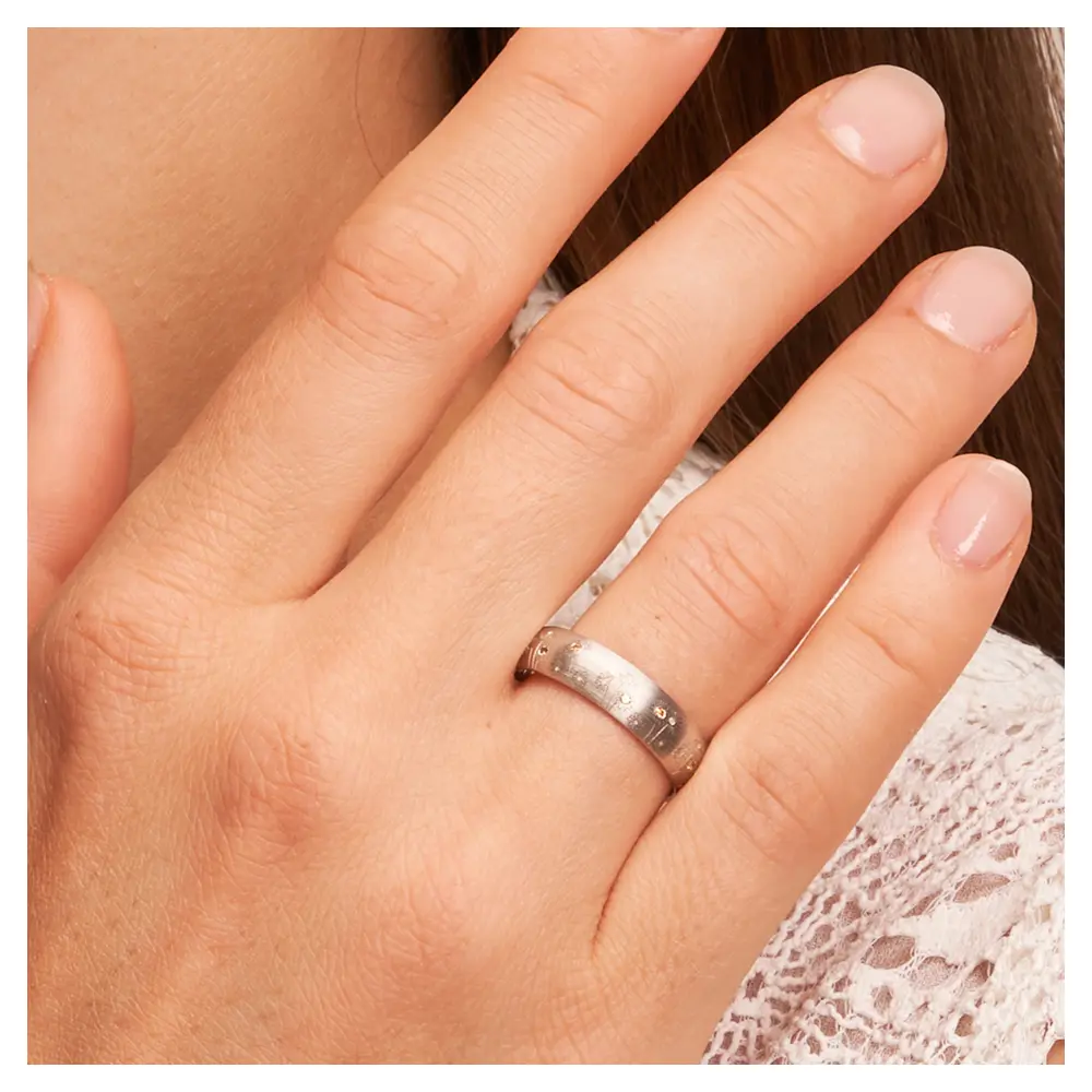 Weißgold Trauring mit Blumen als Dekor und vierzehn Diamanten auf Hand am Gesicht im Zoom