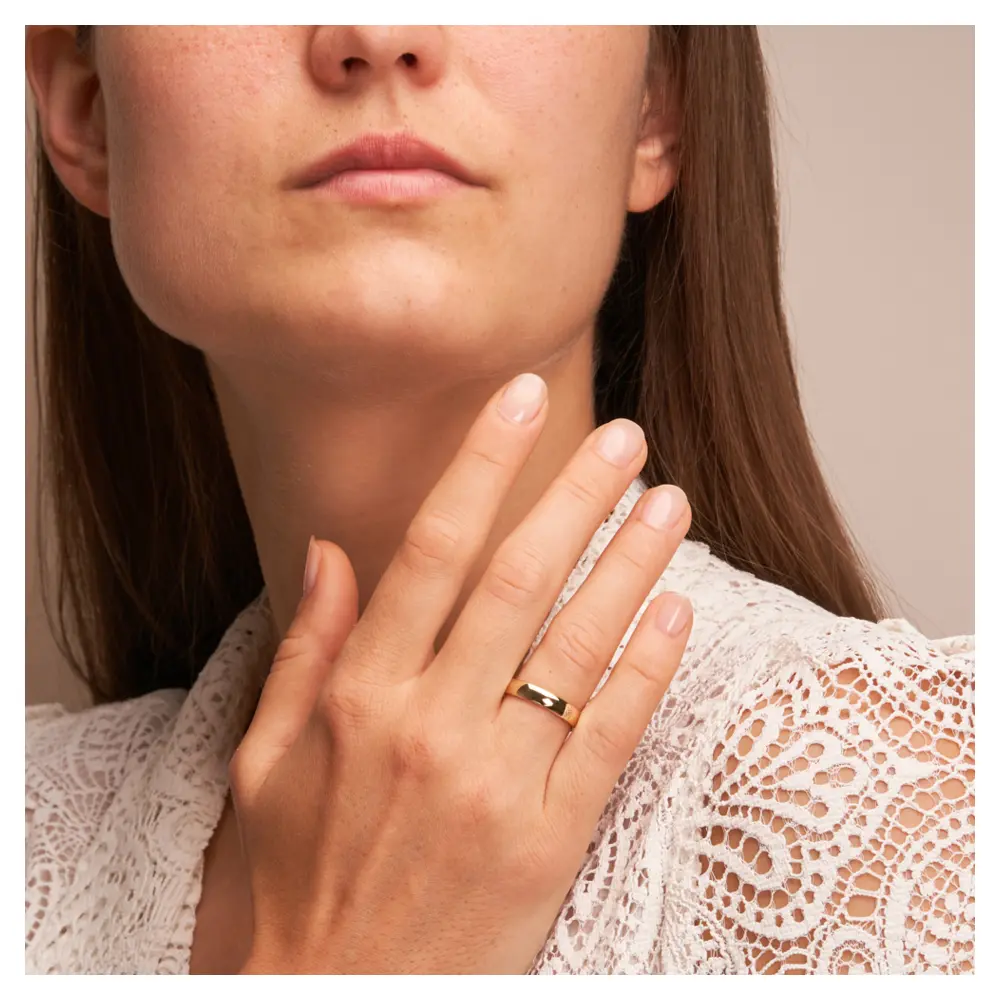 Eheringe aus poliertem Gelbgold mit 1,4 mm Stärke und 4 mm Breite auf Hand am Gesicht