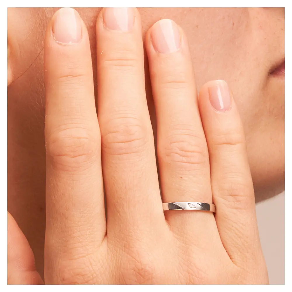 Platin Ehering mit Diamanten in 2,5 mm Breite auf Hand am Gesicht im Zoom