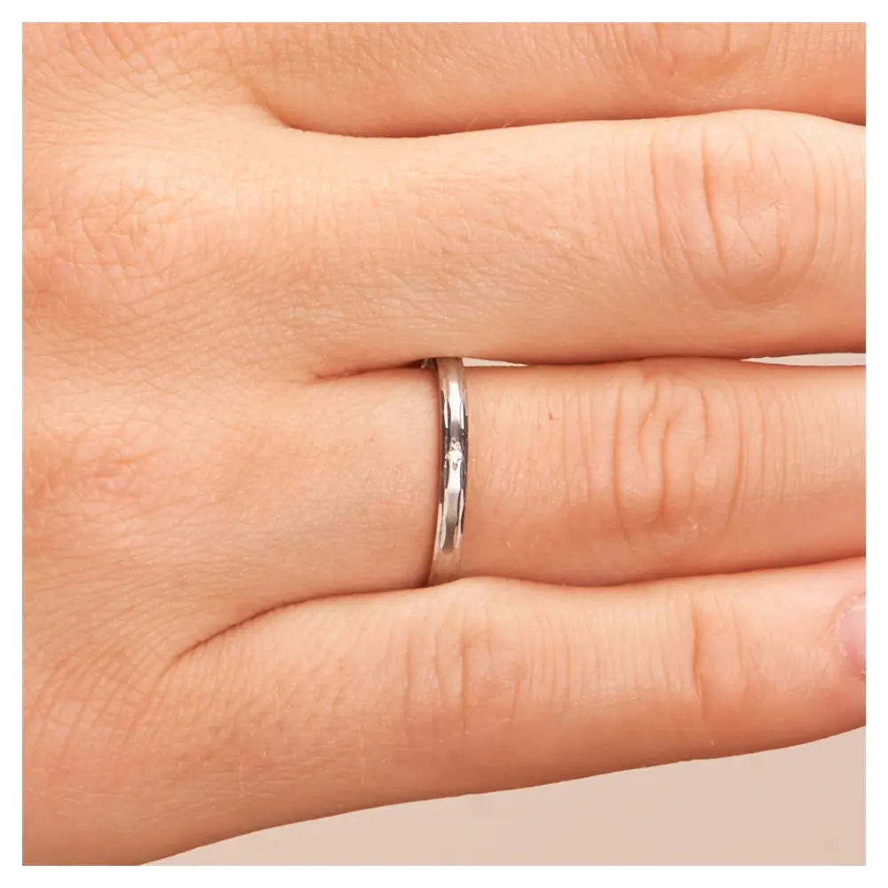 Trauringe Palladium 2 mm breit mit Randmuster und Diamant auf Hand im Zoom
