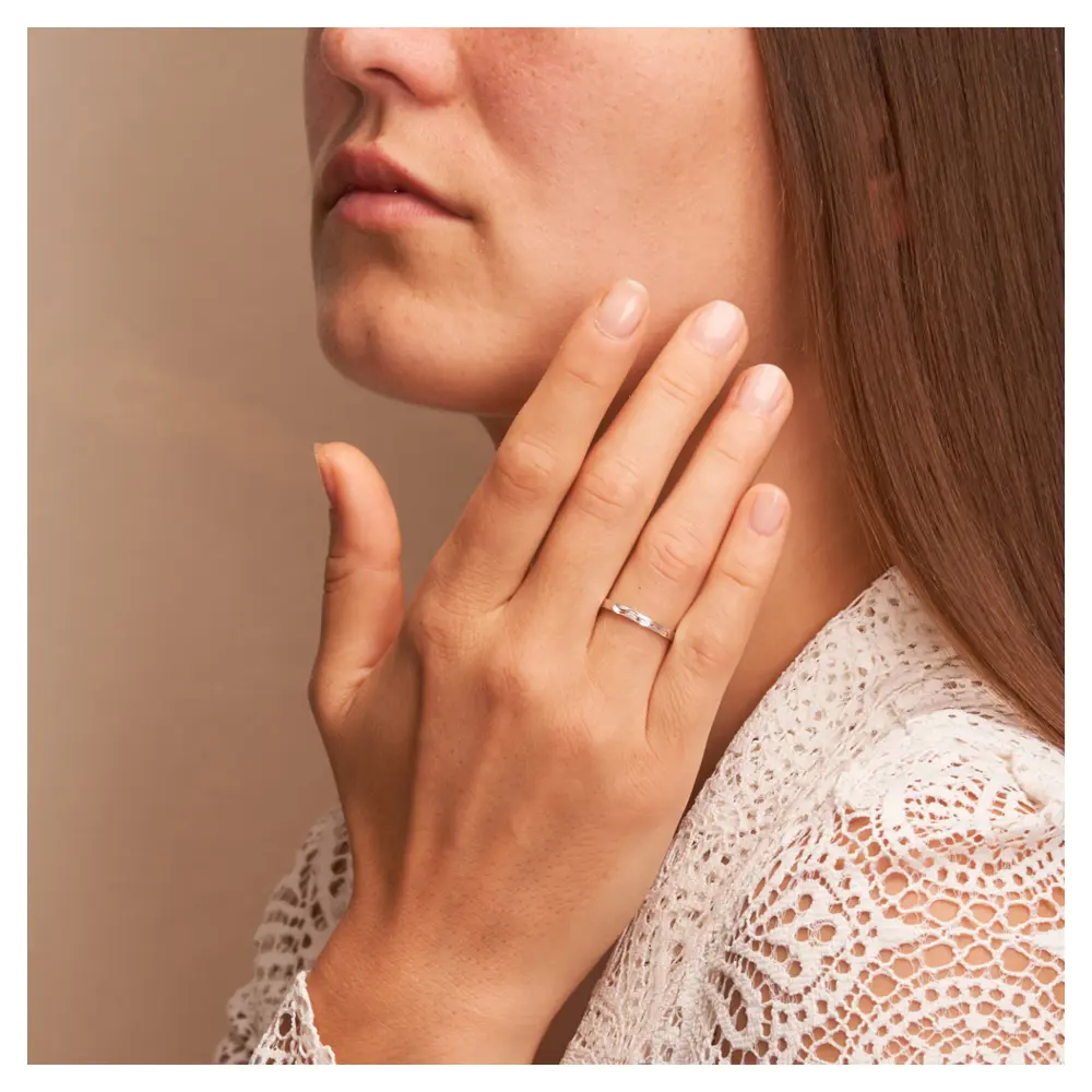 Weissgold Trauringe schmal mit Wellenmuster auf Hand am Gesicht