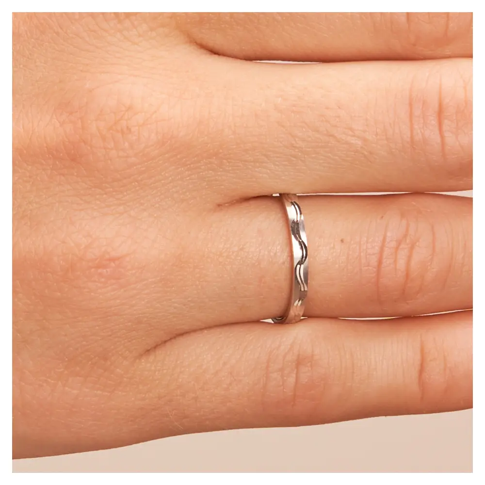 Weissgold Trauringe schmal mit Wellenmuster auf Hand im Zoom