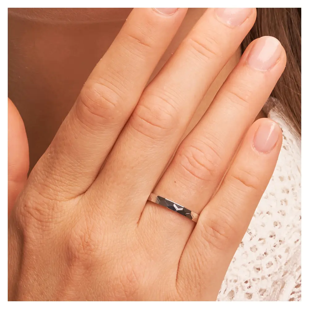 Platin Eheringe mit geometirschem Muster auf Hand am Gesicht im Zoom