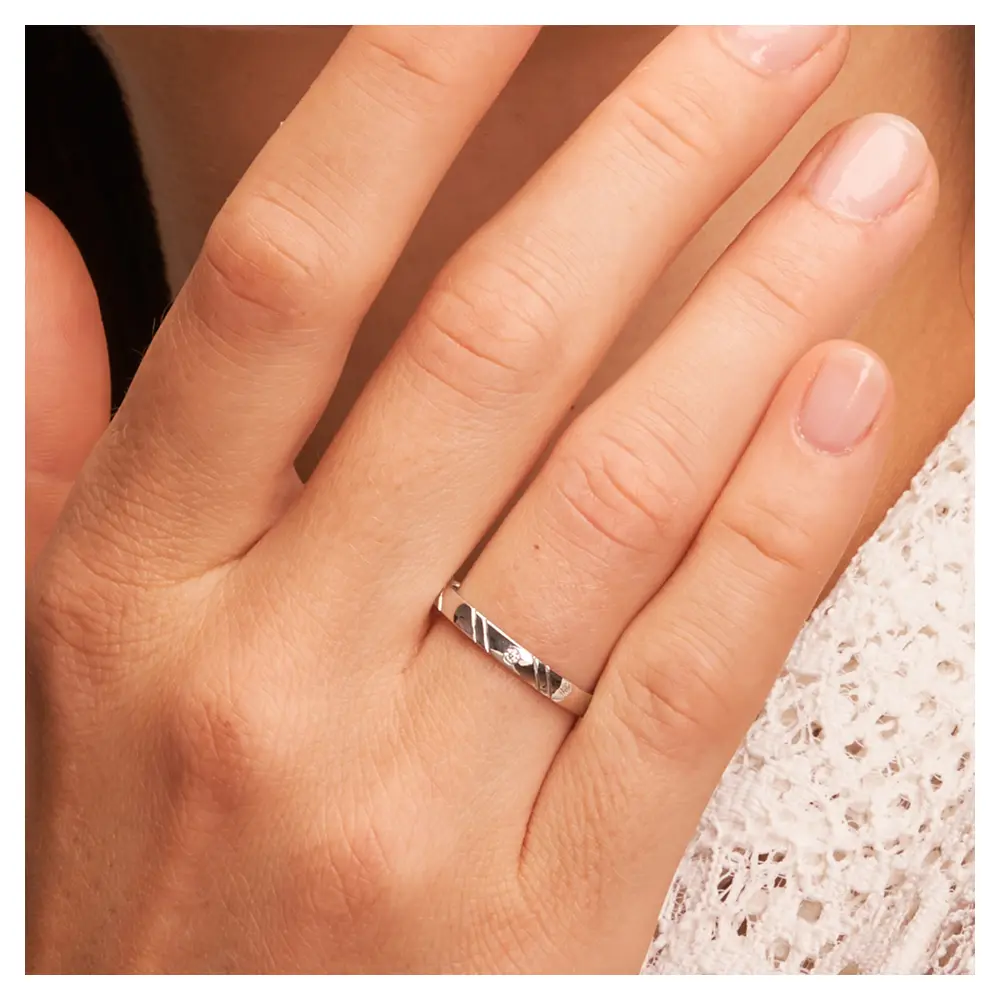 Platin Eheringe in 2,5 mm Breite mit Rillenmuster und Diamanten auf Hand am Gesicht im Zoom