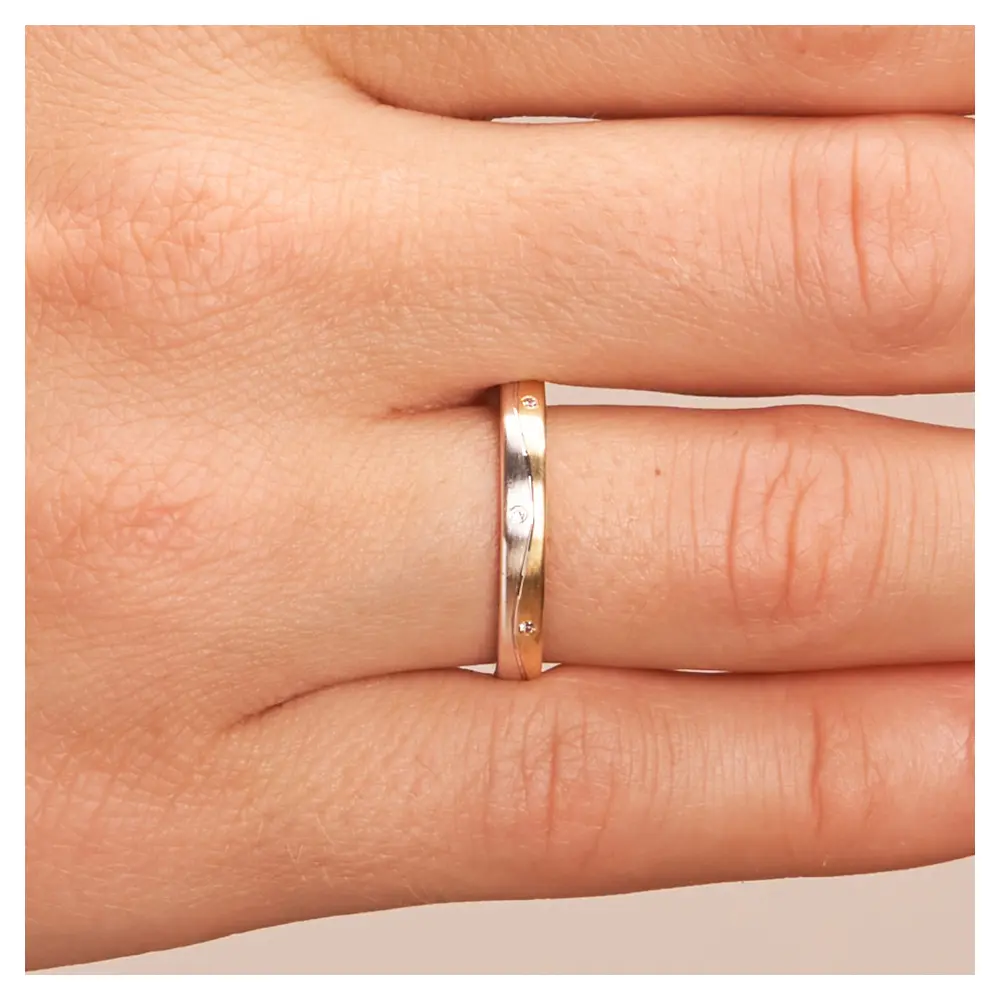 Gelbgold und Weissgold Eheringe mit Längsmattierung und drei Diamanten auf Hand im Zoom