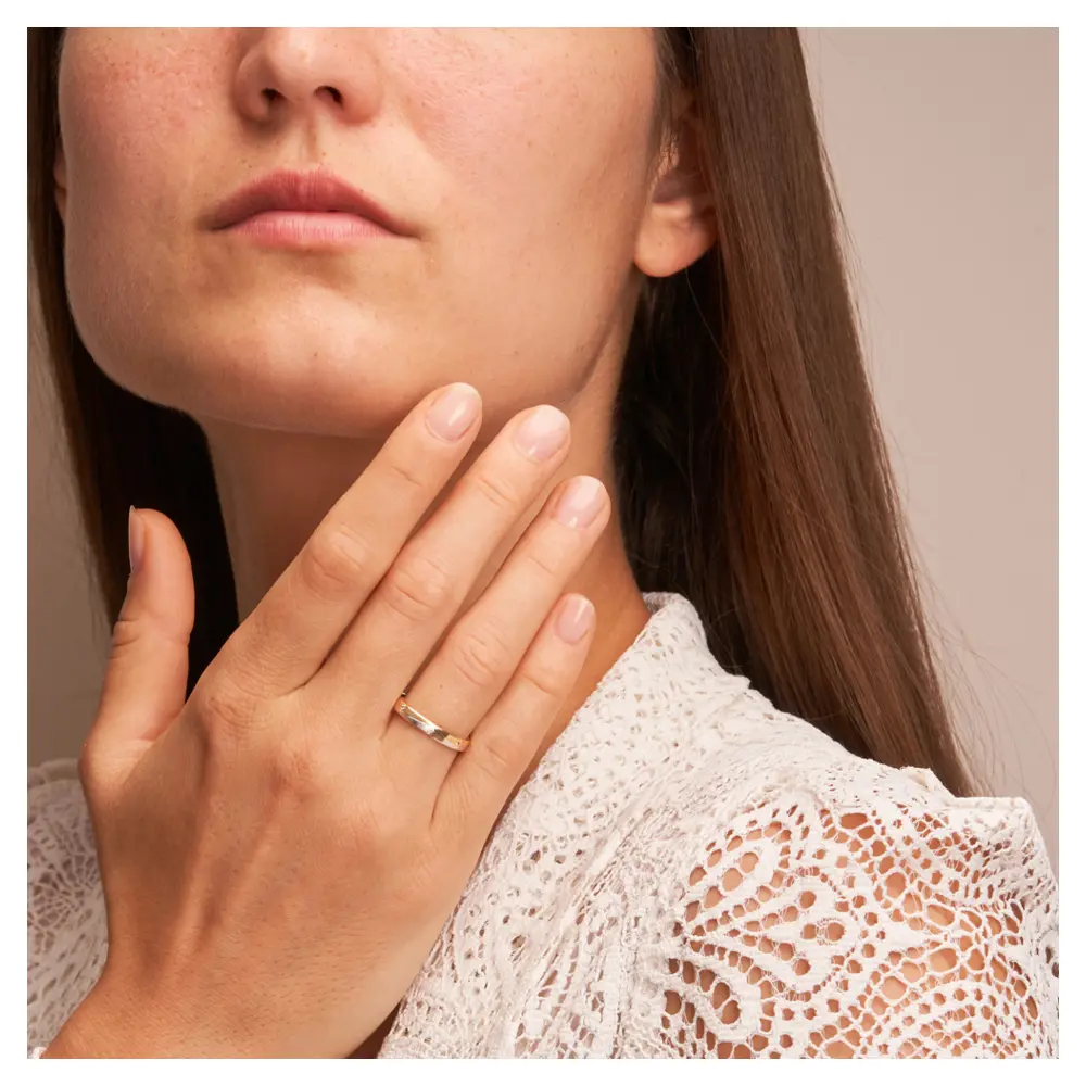 Gelbgold und Weissgold Eheringe mit Längsmattierung und Diamanten auf Hand am Gesicht