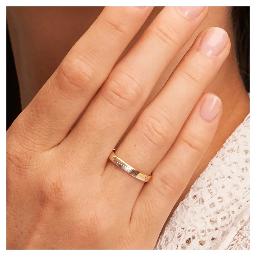 Gelbgold und Weissgold Eheringe mit Längsmattierung und Diamanten auf Hand am Gesicht im Zoom