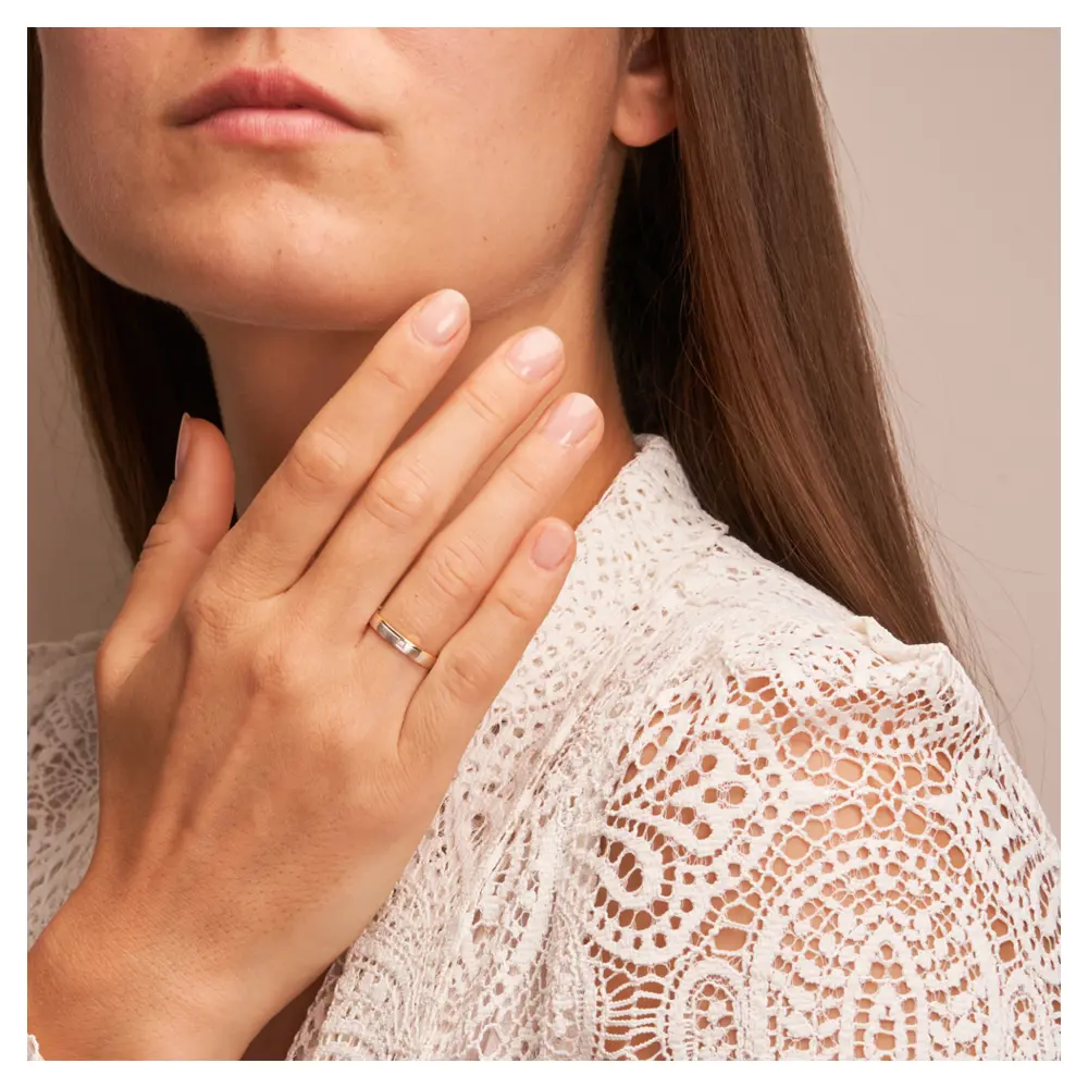 Gelbgold und Weissgold Ehering mit Diamanten und Mattierung auf Hand am Gesicht