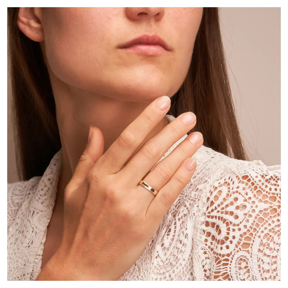 Gelbgold und Weissgold Ehering mit Diamanten Polierung und Sandmattierung auf Hand am Gesicht