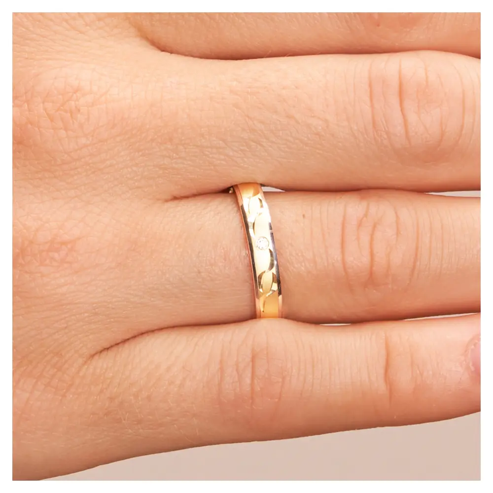 Gelbgold und Weissgold Ehering mit Sichelmustern und Diamant auf Hand im Zoom