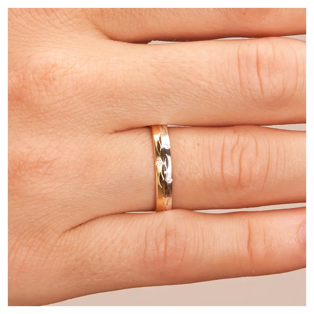 Gelbgold und Weissgold Ehering mit Muster aus polierten Halbmonden und Diamant auf Hand im Zoom