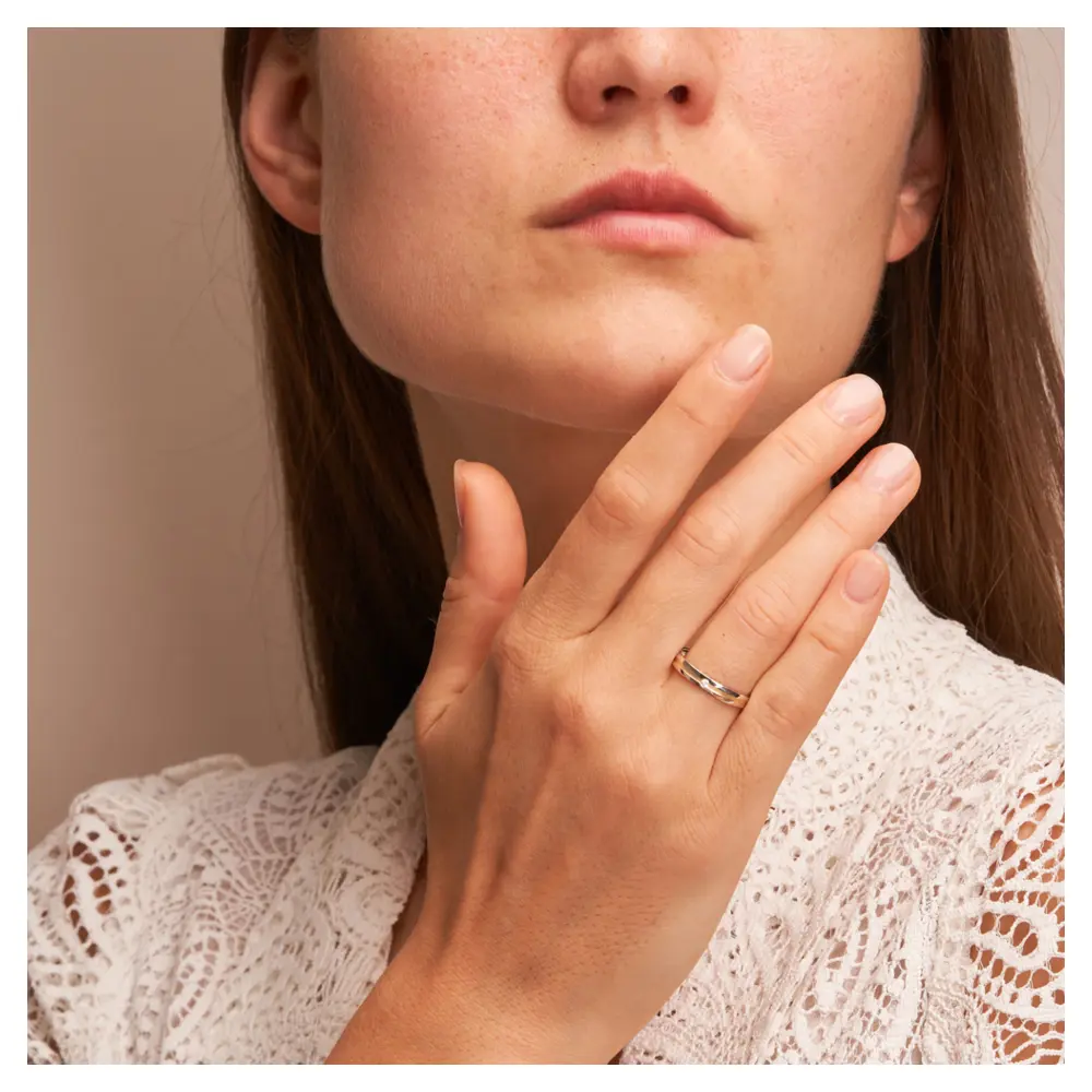 Gelbgold und Weissgold Ehering mit Diamanten und sandmattem Mittelstreifen auf Hand am Gesicht