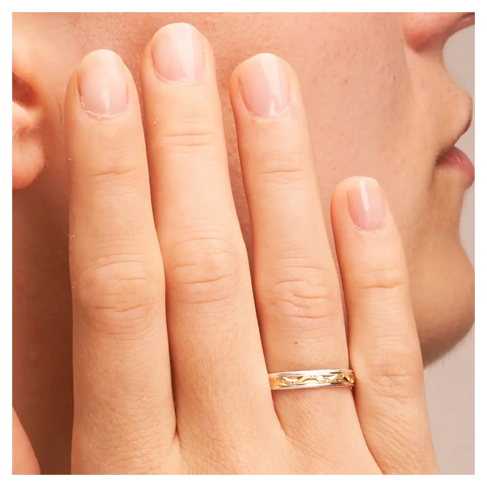 Gelb-&Weissgold Eheringe mit Kreisen und Halbmonden und Diamant auf Hand am Gesicht im Zoom