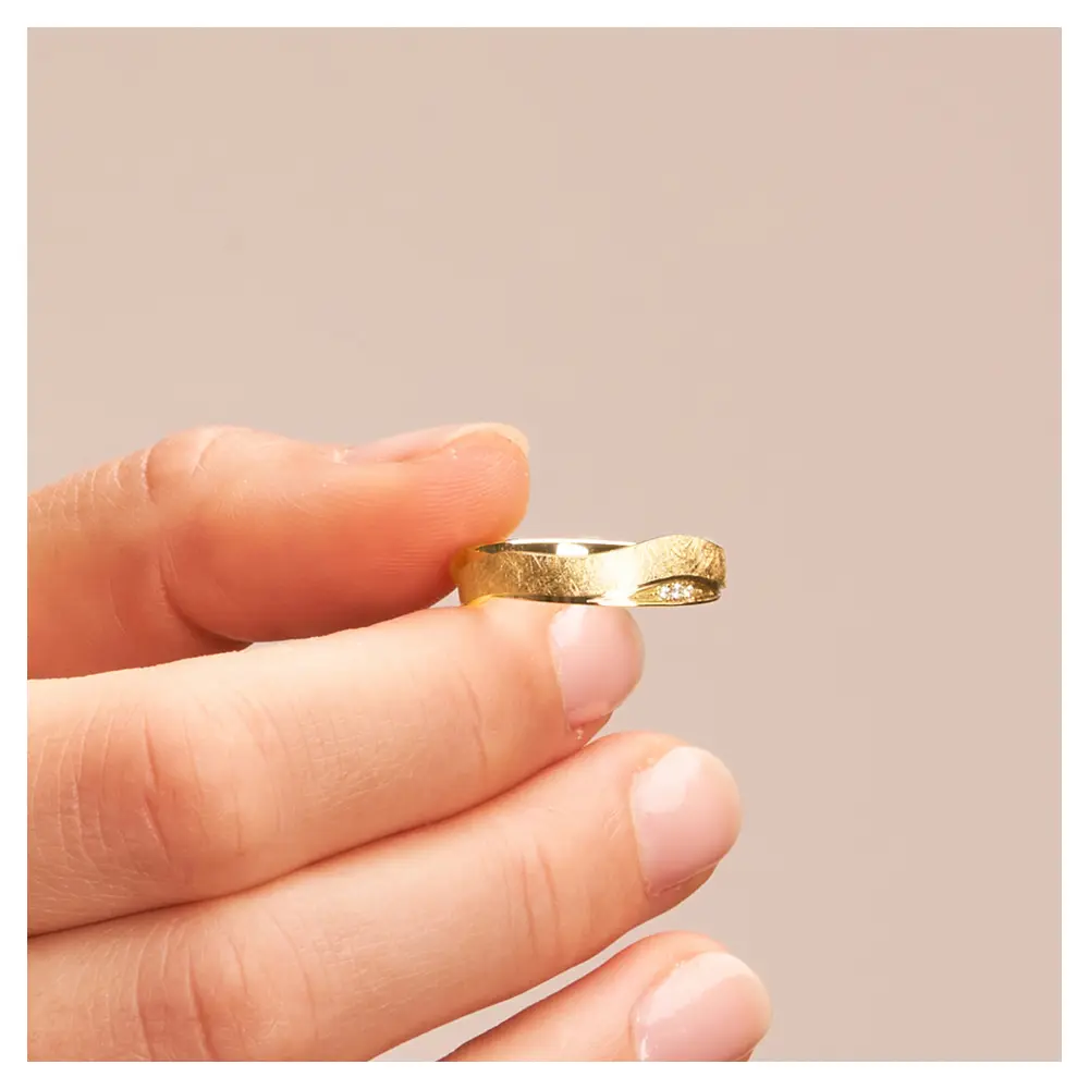Gelbgold Eheringen mit eismatter und polierter Flächen und Diamanten in Hand im Zoom