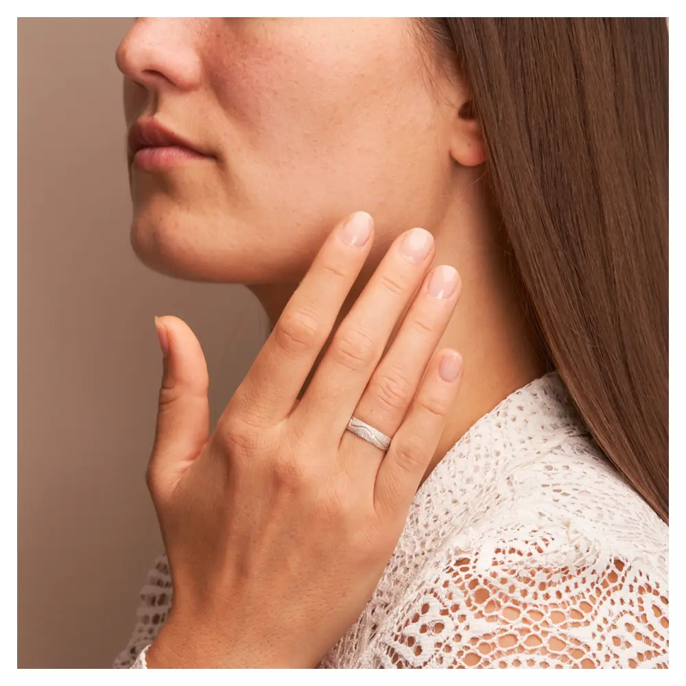 Weissgold Eheringe mit Diamanten und strukturierter Oberfläche auf Hand