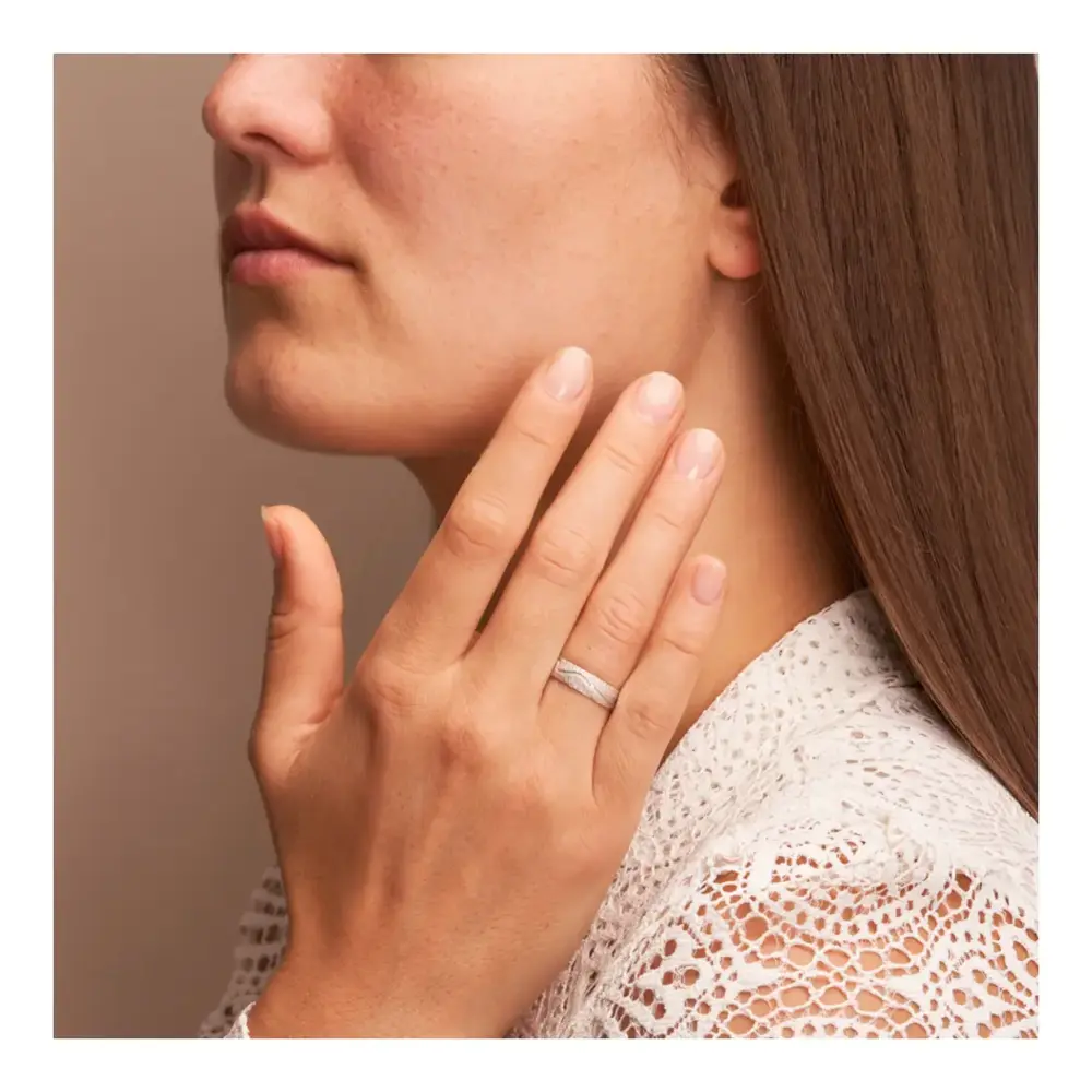 Weissgold Eheringe mit Diamanten und strukturierter Oberfläche auf Hand