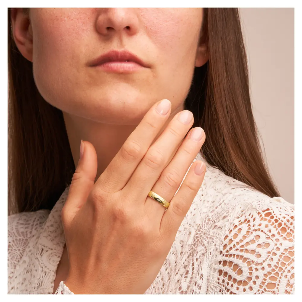 Poliert und gehämmert gestaltete Eheringe aus Gelbgold mit Diamanten in quadratischer Form auf Hand