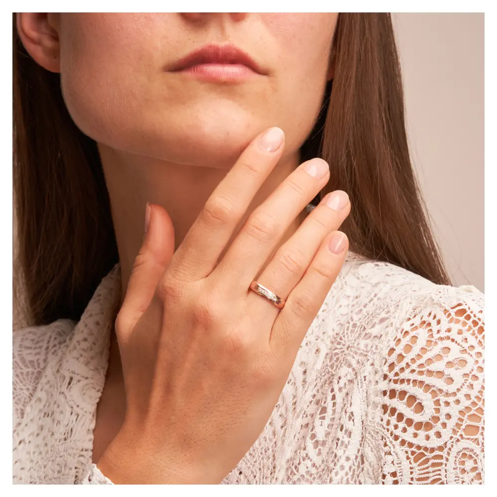 Hammerschlag Roségold Eheringe mit 7 Diamanten und polierten Rändern auf Hand am Gesicht