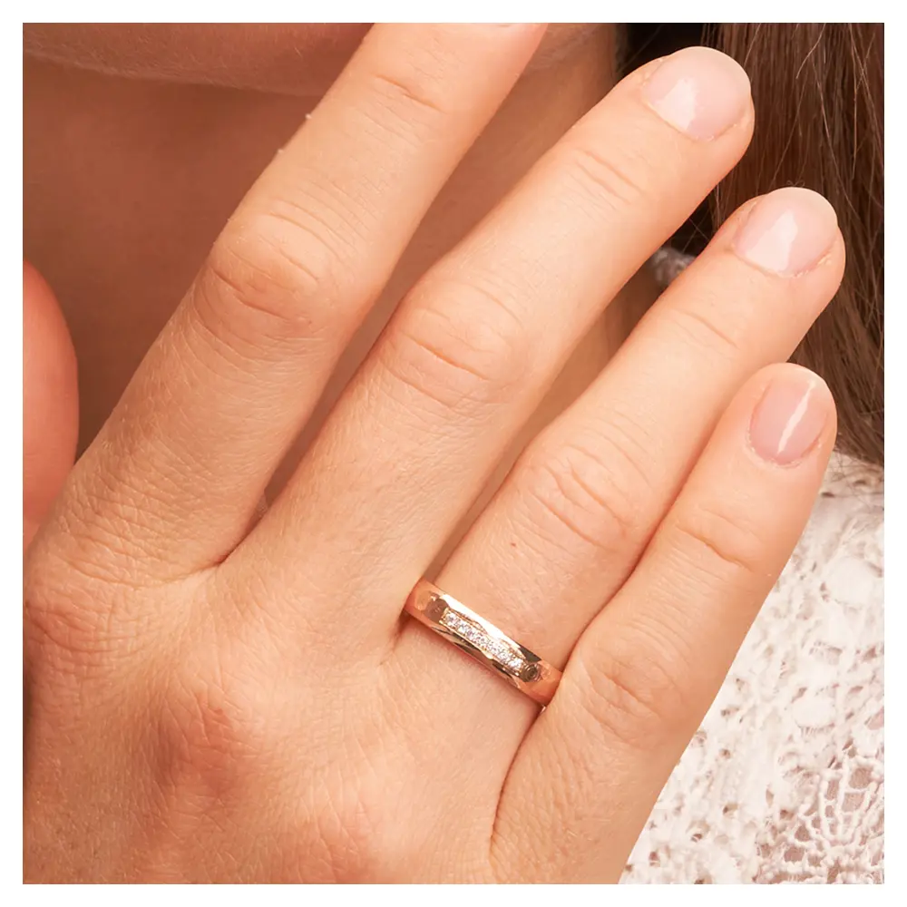 Hammerschlag Roségold Eheringe mit 7 Diamanten und polierten Rändern auf Hand am Gesicht im Zoom
