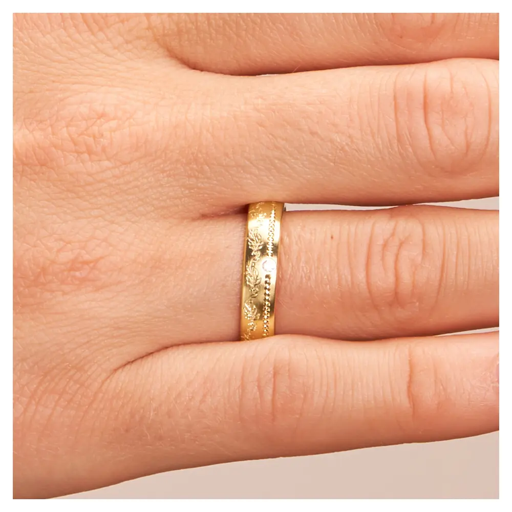 Mattierter Ehering aus Gelbgold mit Diamanten und Blumenmuster auf Hand im Zoom