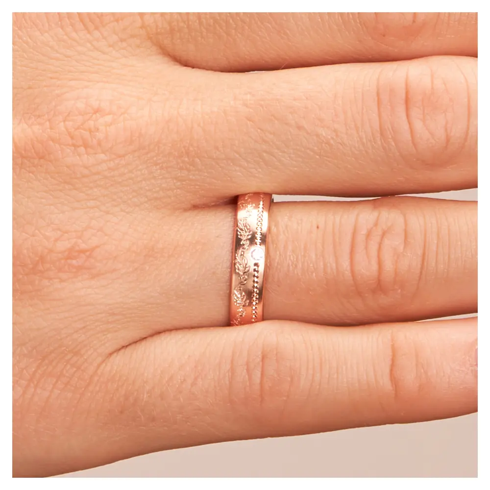 Roségold Ehering mit Diamanten und blumigem Muster auf Hand im Zoom