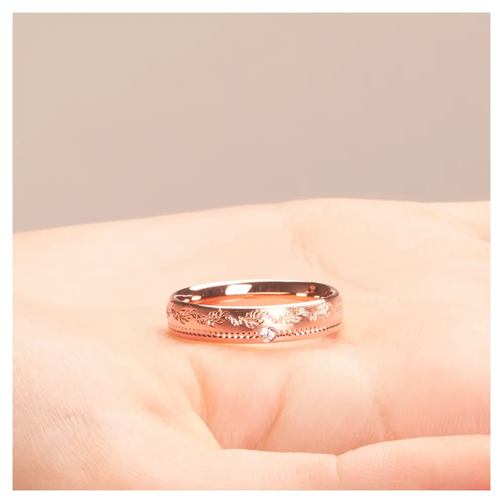 Roségold Ehering mit Diamanten und blumigem Muster auf Hand