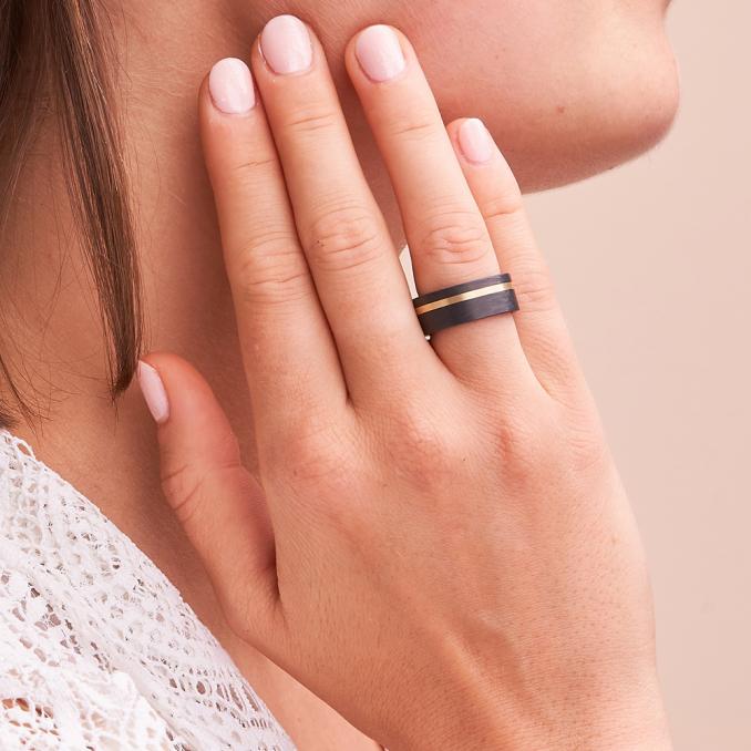 Aufnahme von Partnerringen aus gemasertem Carbon mit Gelbgold Seitenstreifen auf Hand