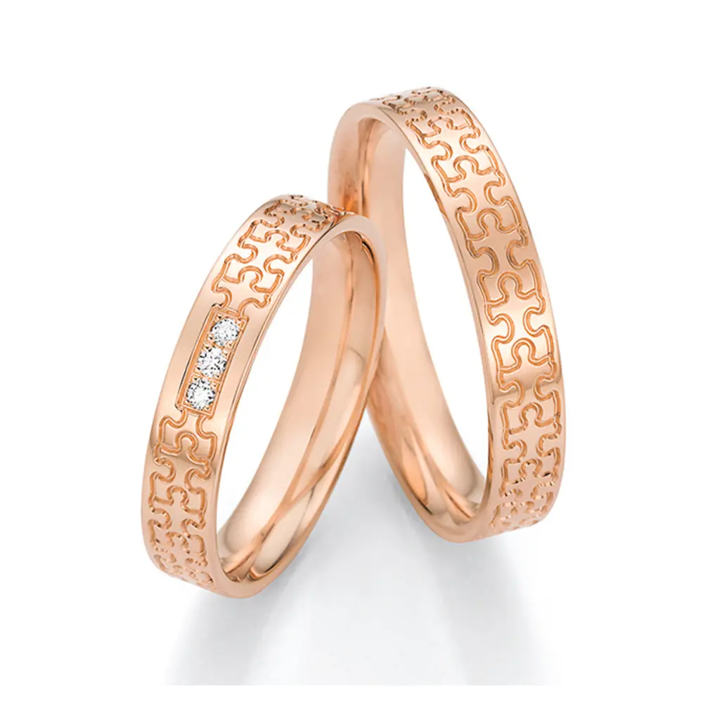 Rotgold Eheringe in Puzzle-Optik mit drei Diamanten in Reihe