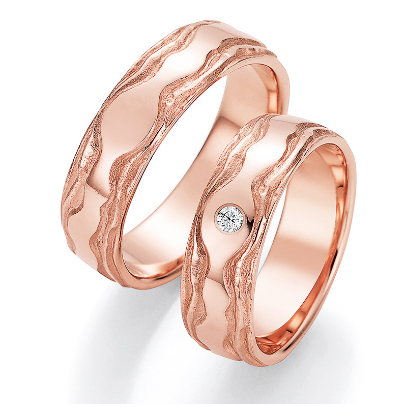  	Aufnahme der Trauringe aus glattem Roségold mit sandmatten Rillen und Diamanten 