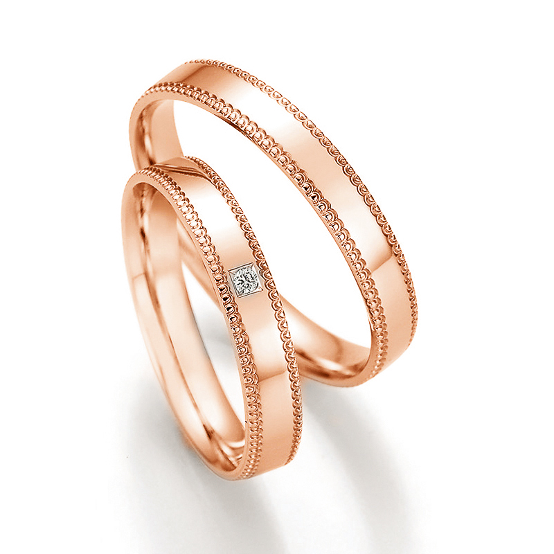 Aufnahme der Eheringe aus Rotgold mit Schnörkel an Rändern und Diamanten