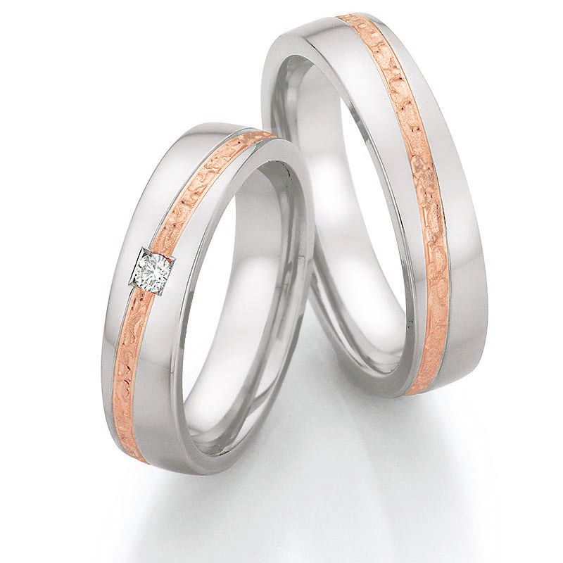 Aufnahme von Trauringen aus Edelstahl mit Roségoldstreifen und Diamanten in viereckiger Fassung