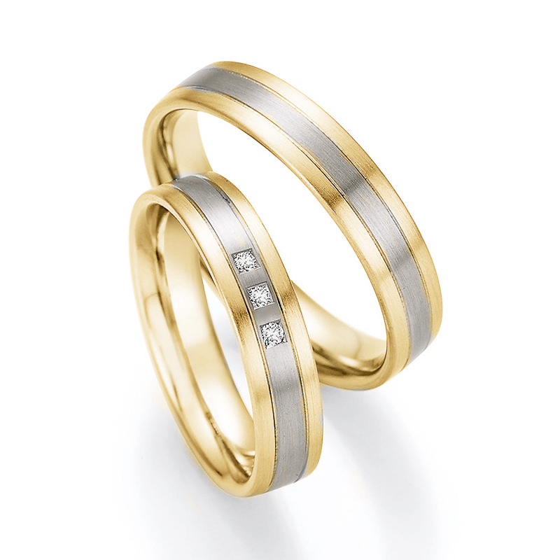 Aufnahme von Trauringen in Gelbgold und Palladium 500 längsmatt mit drei weißen Diamanten
