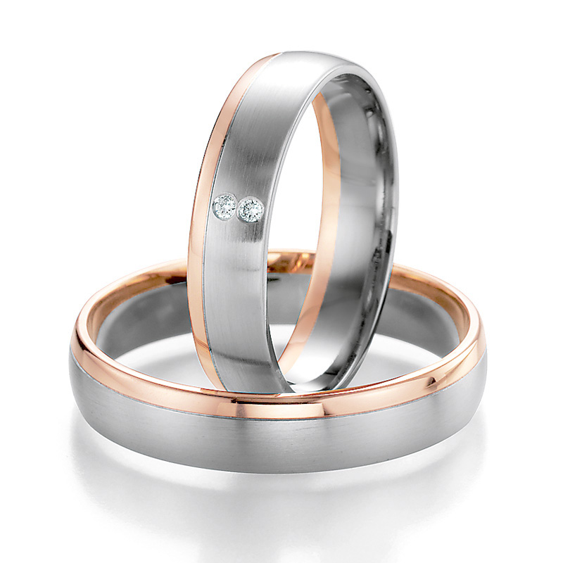 Aufnahme von Trauringen aus Palladium 500 und Roségold am Rand mit zwei Diamanten