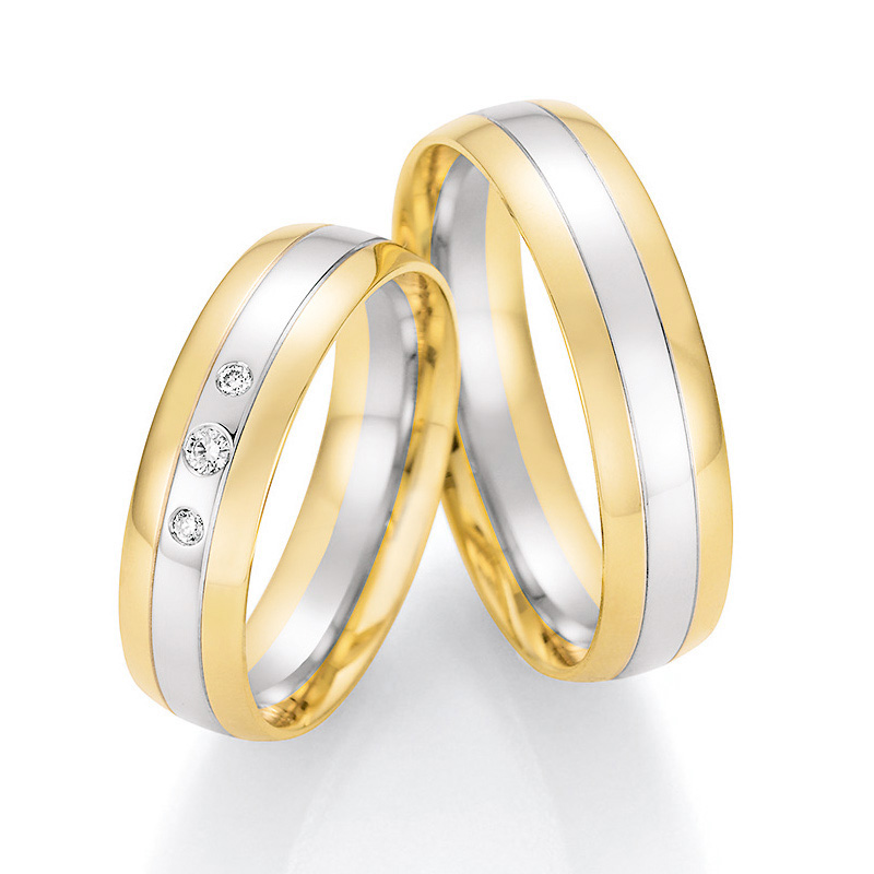 Aufnahme von Trauringen aus Weißgold mit Gelbgoldrändern und mittigen Diamanten