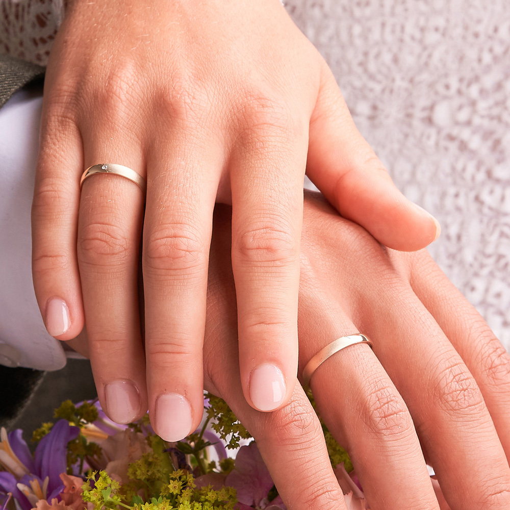 Aufnahme der schmalen Gelbgold Eheringe mit Zweierlei Oberflächen und Diamanten auf Hand 