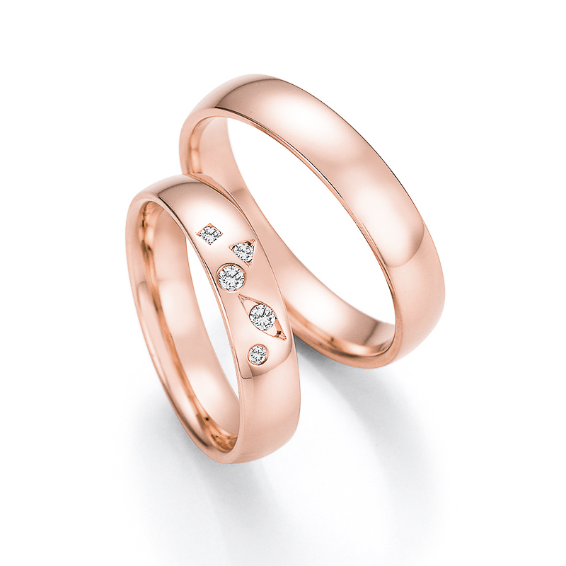 Aufnahme der Trauringe aus poliertem Roségold mit 5 Diamanten in Vertiefungen verschiedener Form 