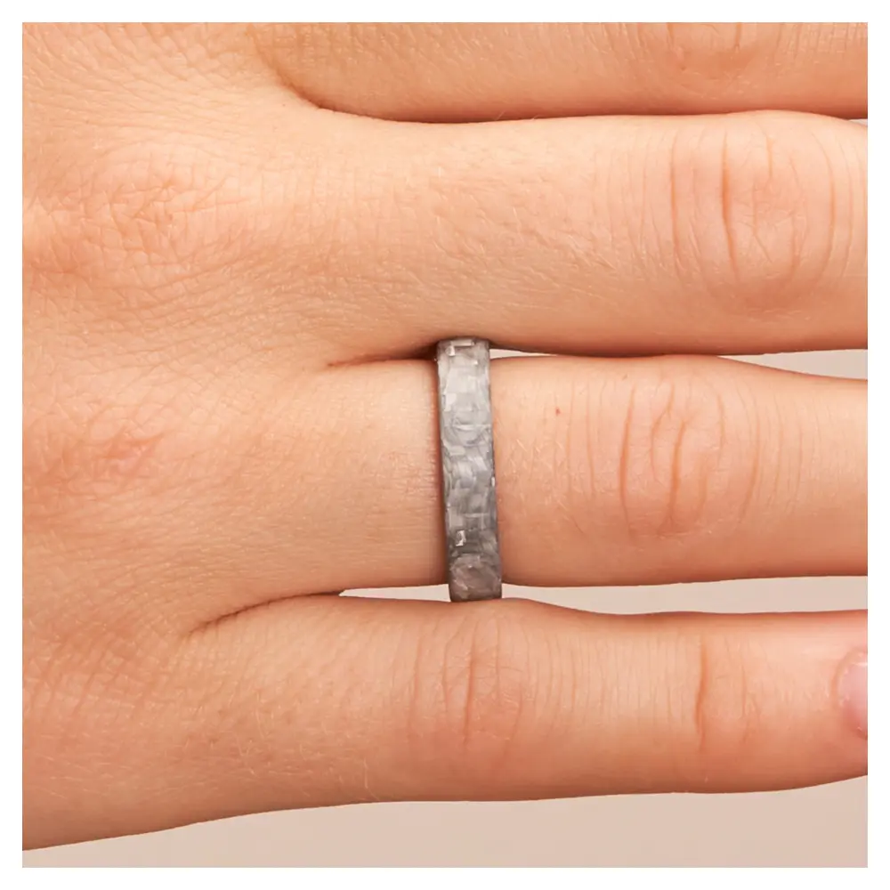 Eheringe aus grauem Carbon auf Hand am Gesicht