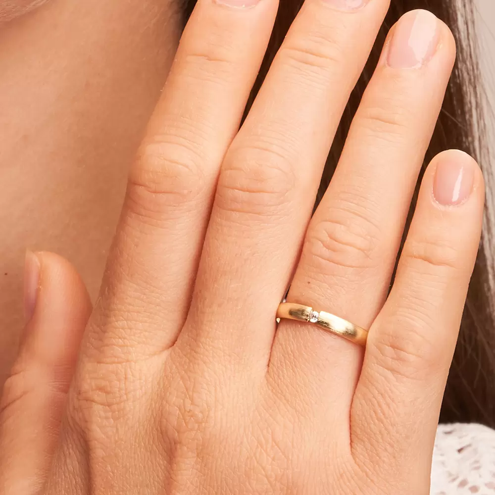 Gelbgold Eheringe mit 0,04 Karat Diamanten und längsmatter Oberfläche auf Hand im Zoom