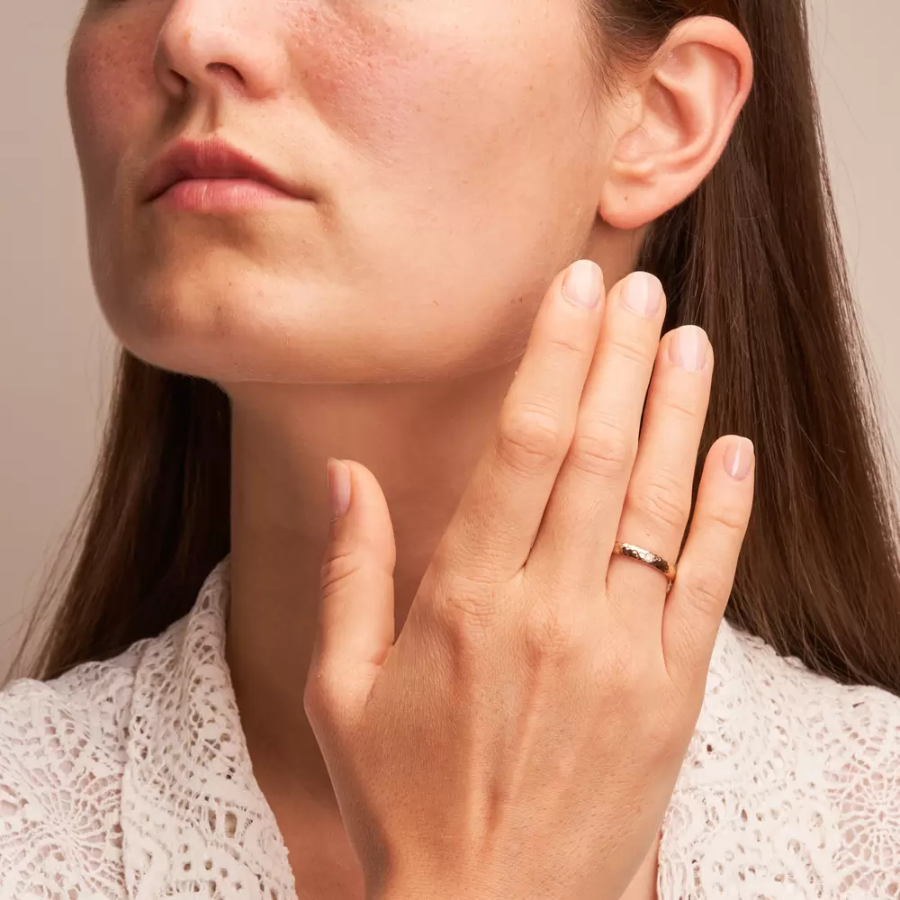 Ehering aus Herbstgold mit 0,03 Karat Diamanten und Hammerschlag auf Hand
