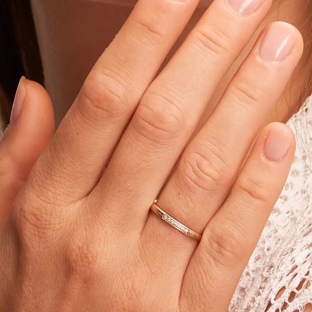 Schmaler Ehering aus Herbstgold in Quermattierung mit 7 Diamanten auf Hand im Zoom