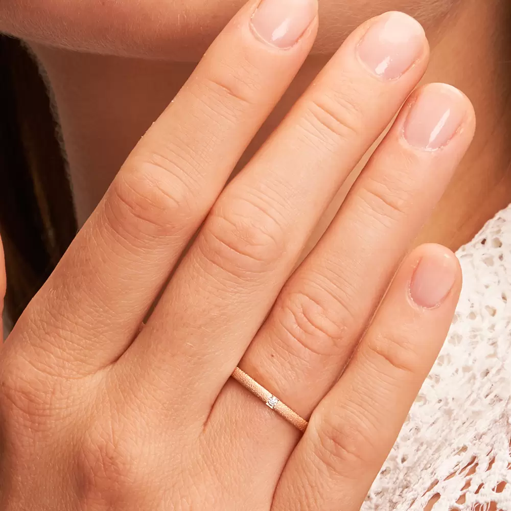 Ehering aus Roségold mit Oberflächenstrukturierung und 0,02 Karat Diamanten auf Hand im Zoom