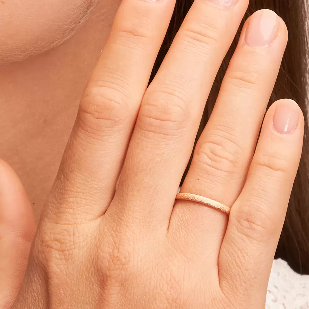 Ehering aus Roségold mit Oberflächenstrukturierung auf Hand im Zoom